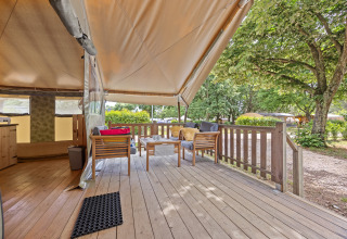 Uitzicht op een gezellige veranda met houten meubels en overkapping bij een Safaritent Relax op de camping.