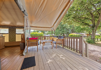 Vista di una terrazza accogliente con mobili in legno e tenda nella Safaritent Relax in un campeggio.