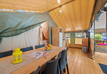 Vista interna della Safaritent Relax con tavolo di legno, sedie, cucina e ambiente accogliente da tenda.