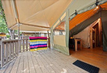 Buiten houten terras en ingang van de Safaritent Relax met kleurrijke stof en comfortabele inrichting.