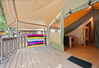 Udendørs træterrasse og indgang til Safaritent Relax med farverige striber og moderne campingindretning.