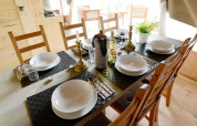 Tavola da pranzo elegante per sei in una tenda safari, con piatti, bicchieri e bottiglie di vino.