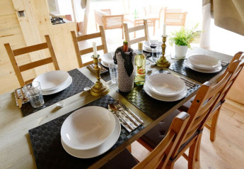 Tavola da pranzo elegante per sei in una tenda safari, con piatti, bicchieri e bottiglie di vino.