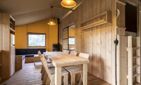 Interno della Safaritent Bella Lodge al Camping Valkanela in Croazia, con zona pranzo in legno.