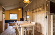 Interno della Safaritent Bella Lodge al Camping Valkanela in Croazia, con zona pranzo in legno.