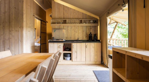 Vue intérieure de la Safaritent Bella Lodge au Camping Valkanela en Croatie, avec cuisine et coin repas en bois.