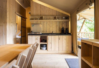 Vista interna di Safaritent Bella Lodge al Camping Valkanela, Croazia, con cucina e zona pranzo in legno.