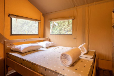 Vista interna di un letto con asciugamani arrotolati e cuscini nella Safaritent Bella Lodge al Camping Valkanela, Croazia.