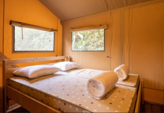 Vue intérieure d'un lit avec serviettes roulées et oreillers dans Safaritent Bella Lodge au Camping Valkanela, Croatie.