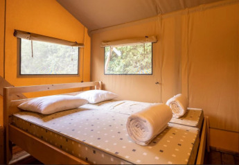 Vista interior de una cama con toallas enrolladas y almohadas en Safaritent Bella Lodge en Camping Valkanela, Croacia.