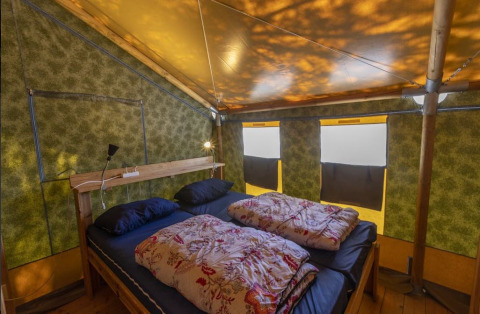 Interno della Safaritent Sunset con letto matrimoniale, dettagli in legno e finestre al Camping Polari, Croazia.