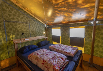 Interno della Safaritent Sunset con letto matrimoniale, dettagli in legno e finestre al Camping Polari, Croazia.