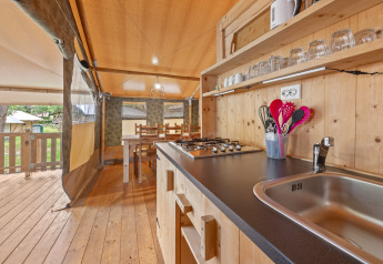 Keuken van een safaritent met houten inrichting, gasvuur en eetgedeelte op Camping Polari in Kroatië.