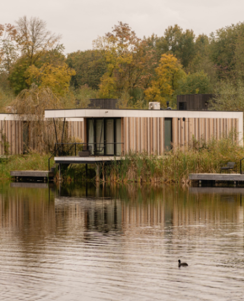 Moderne Waterlodge Sauna bij Resort de Parel in Nederland, aan een meer omringd door herfstbomen.