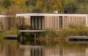 Moderne Waterlodge Sauna bij Resort de Parel in Nederland, aan het water en omgeven door herfstkleurige bomen.