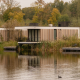 Waterlodge Sauna moderne au Resort de Parel, Pays-Bas, sur le lac entouré d’arbres aux couleurs d’automne.
