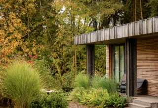 Lodge en bois moderne au Resort de Parel, Pays-Bas, entourée de verdure luxuriante et d’arbres.