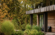 Lodge en bois moderne au Resort de Parel, Pays-Bas, entourée de verdure luxuriante et d’arbres.