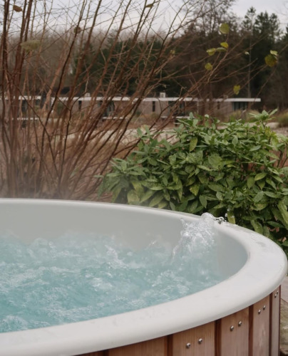 Outdoor hot tub at Villa Roof Terrace + Hot tub at Resort de Parel in the Netherlands, surrounded by greenery.