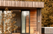 Modern wooden cabin with large glass doors and jacuzzi in the woods at Lodge Jacuzzi, Resort de Parel, Netherlands.