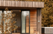 Moderne houten lodge met grote ramen en jacuzzi, omgeven door bos, bij Resort de Parel, Nederland.