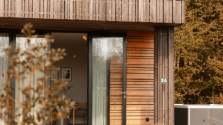 Lodge moderno in legno con porte a vetro e jacuzzi immerso nei boschi presso Resort de Parel, Paesi Bassi.