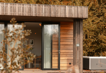 Modern wooden cabin with large glass doors and jacuzzi in the woods at Lodge Jacuzzi, Resort de Parel, Netherlands.