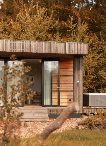 Modern wooden cabin with large glass doors and jacuzzi in the woods at Lodge Jacuzzi, Resort de Parel, Netherlands.