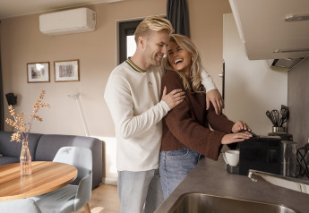 Jong stel geniet samen in een moderne lodge-keuken terwijl ze koffie zetten en vrolijk lachen.