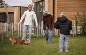 Gezin speelt met hond in de tuin van Parklodge 4 met hondenhek, sauna en hottub in Nederland.