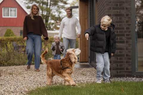 Famille avec chien profite de l’extérieur devant Parklodge 4 avec clôture, sauna et bain chaud aux Pays-Bas.