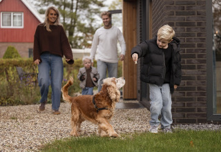 Familie og hund nyder udendørs tid foran Parklodge 4 med hundehegn, sauna og hottub i Nederlandene.