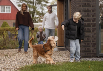 Famille avec chien profite de l’extérieur devant Parklodge 4 avec clôture, sauna et bain chaud aux Pays-Bas.