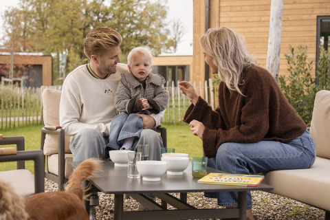 Famille avec enfant et chien prenant le petit-déjeuner dehors à Parklodge 4, Hofparken Wiltershaar, Pays-Bas.