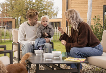 Famille avec enfant et chien prenant le petit-déjeuner dehors à Parklodge 4, Hofparken Wiltershaar, Pays-Bas.