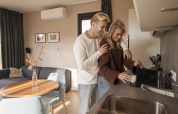 Un jeune couple prépare du café ensemble dans la cuisine moderne d'un lodge chaleureux.