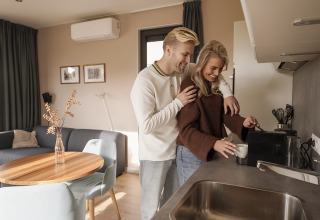 Jong stel maakt samen koffie in de keuken van een moderne, gezellige lodge tijdens een verblijf.