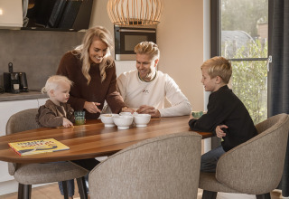 Familie sidder sammen ved et spisebord i Holiday villa Amalia på Hofparken Wiltershaar i Holland.