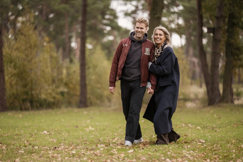Pareja paseando por el césped junto a Holiday villa Amalia 2 con sauna y jacuzzi en Hofparken Wiltershaar, Países Bajos.