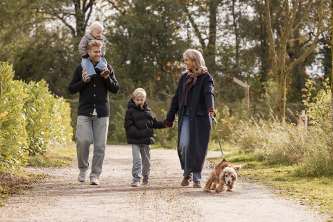Family walking with a dog on a scenic path at Holiday villa Amalia 6 + sauna, enjoying nature together.