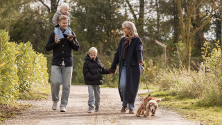 Family walking with a dog on a scenic path at Holiday villa Amalia 6 + sauna, enjoying nature together.