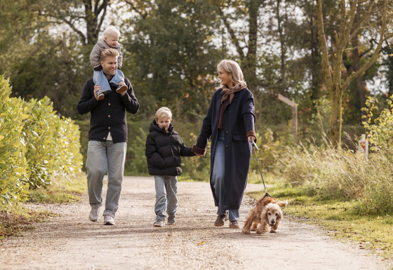 Family walking with a dog on a scenic path at Holiday villa Amalia 6 + sauna, enjoying nature together.