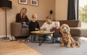 Una familia se relaja junta en la sala de una cabaña acogedora, jugando y acompañados de su perro.