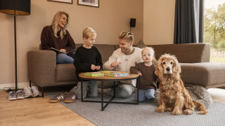 Una familia se relaja junta en la sala de una cabaña acogedora, jugando y acompañados de su perro.