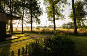 Sonnenuntergang bei Vakantievilla Boslodge 2 mit Sauna im Hofparken Wiltershaar, Niederlande, mit Wald und Wiese.