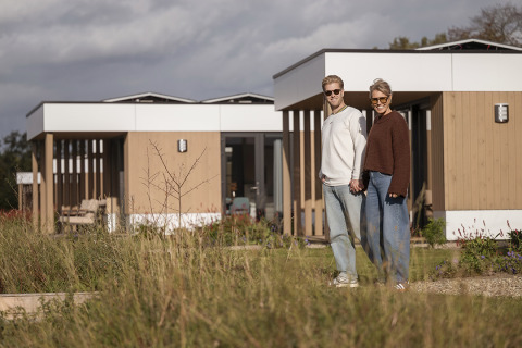 Dos personas de la mano frente a la villa Amalia con sauna y jacuzzi en Hofparken Wiltershaar, Países Bajos.
