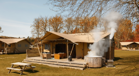 Glamping safaritent La Gran Vida bij Resort de Parel, Nederland, met houten terras en hottub buiten.