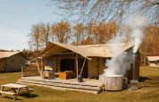 Glamping safaritent La Gran Vida bij Resort de Parel, Nederland, met veranda en hottub buiten.