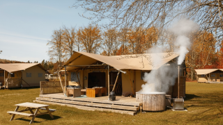 Safari-Glampingzelt La Gran Vida im Resort de Parel, Niederlande, mit Holzterrasse und Whirlpool.