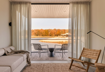 Salon moderne et lumineux d’une Waterlodge au Resort de Parel, Pays-Bas, vue sur lac et forêt d’automne.
